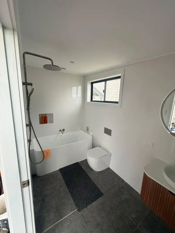 Renovated bathroom with a freestanding bath, rain shower, wall-hung toilet and dark floor tiles