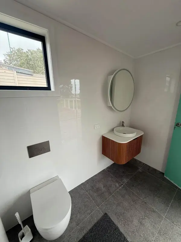 New curved timber vanity and round mirror in a renovated bathroom